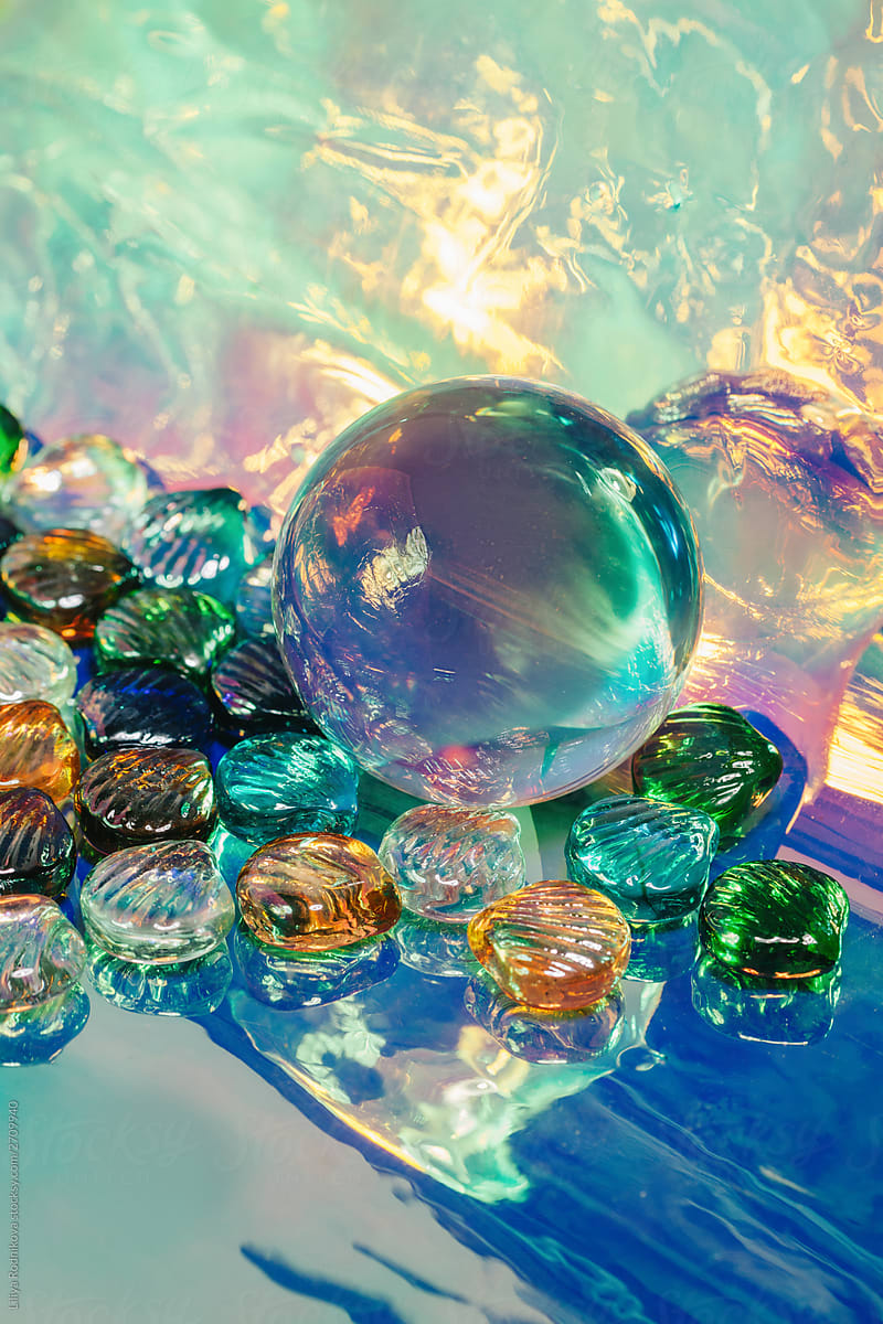 Glass orb with glass sea shells on holographic background