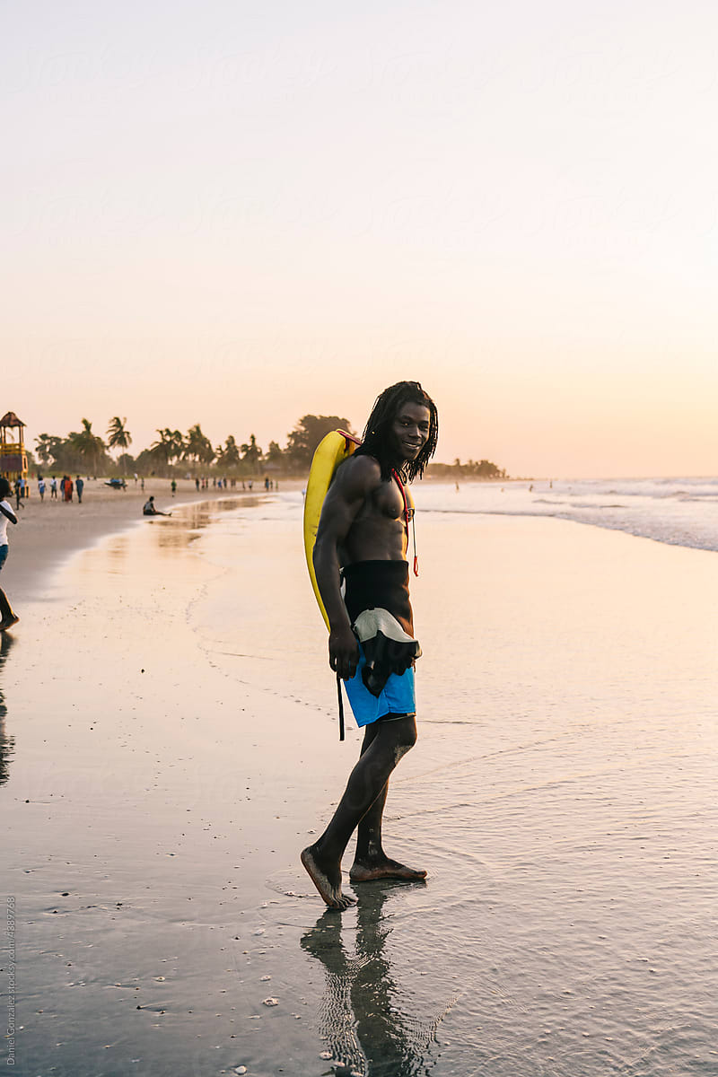 Happy black rescuer on wet seashore in sunset