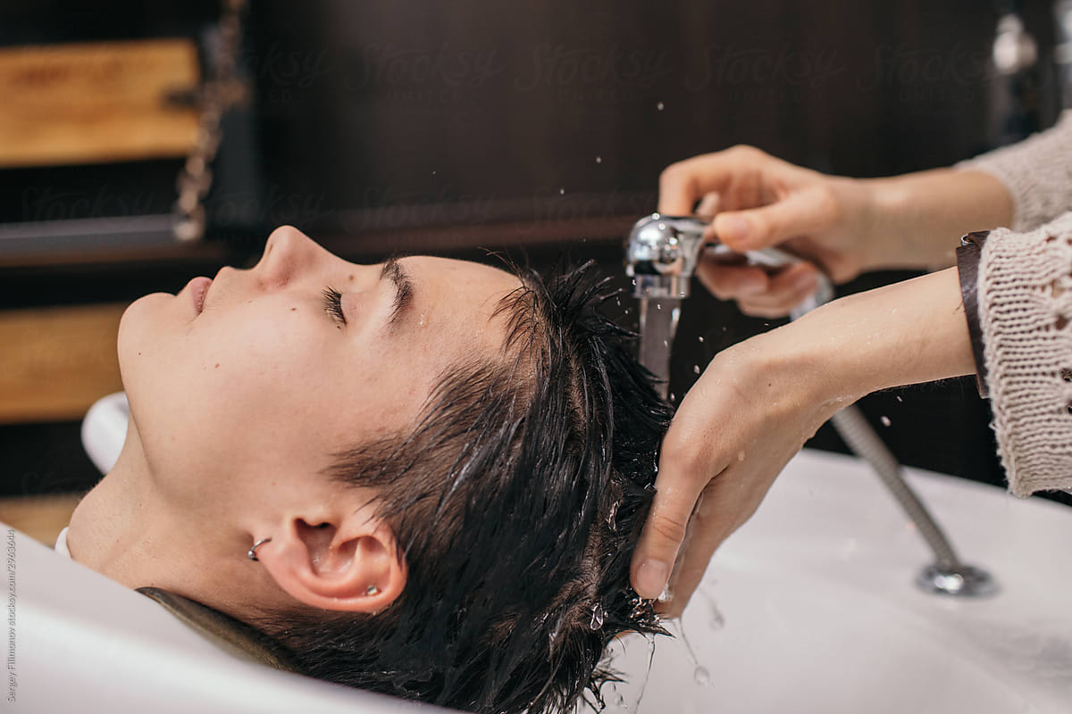 Anonymous hairdresser washing hair of relaxed customer
