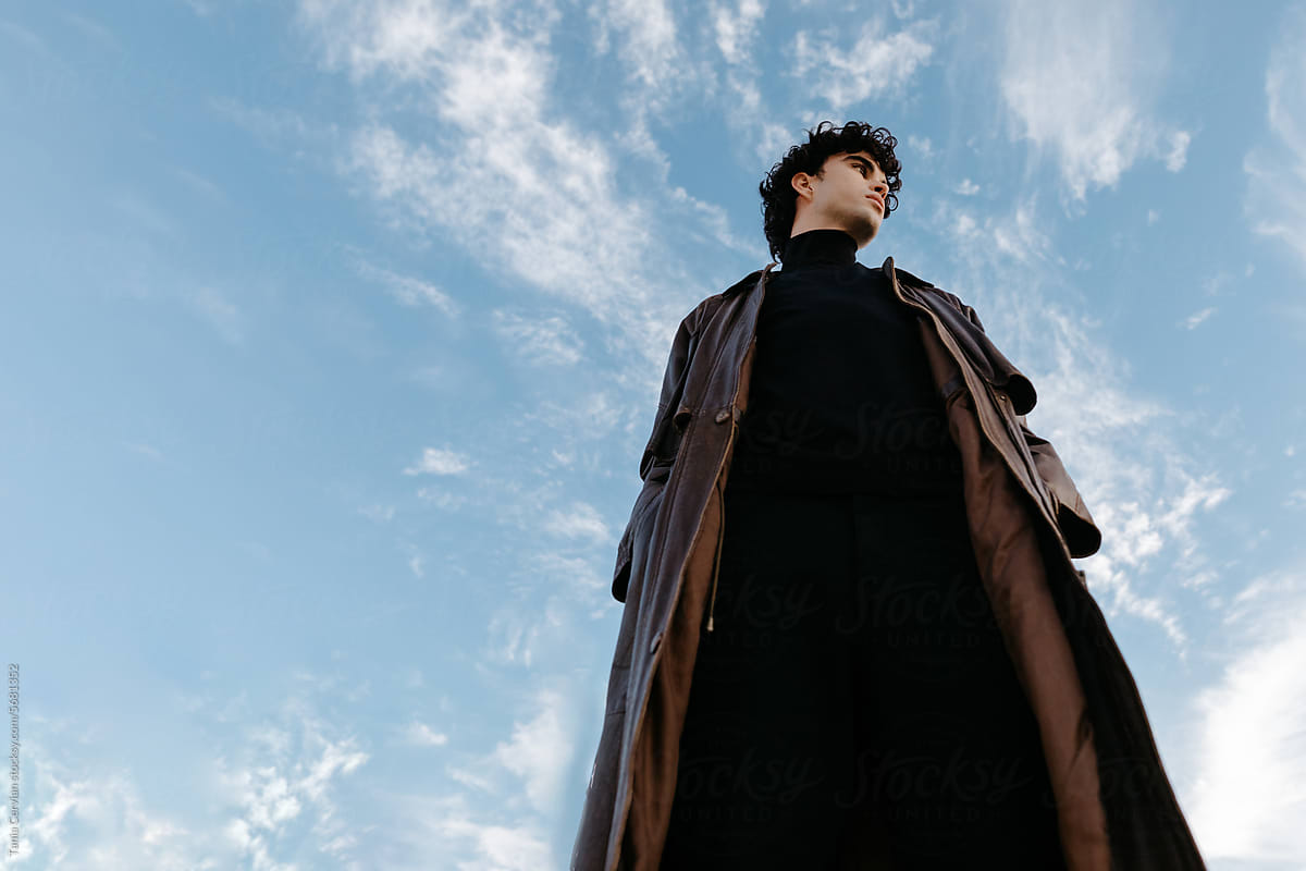 Fashionable young young man standing against blue sky
