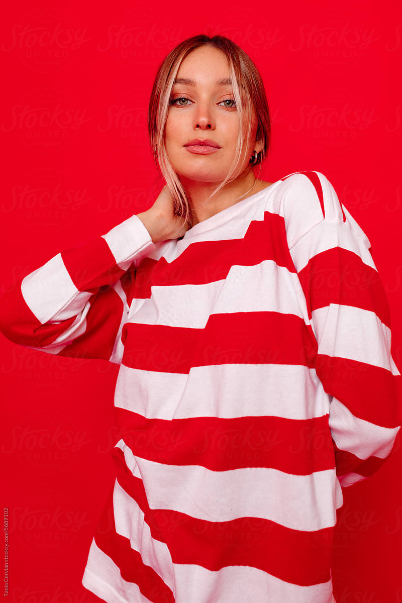 Smiling adult woman in stylish striped sweatshirt looking at camera