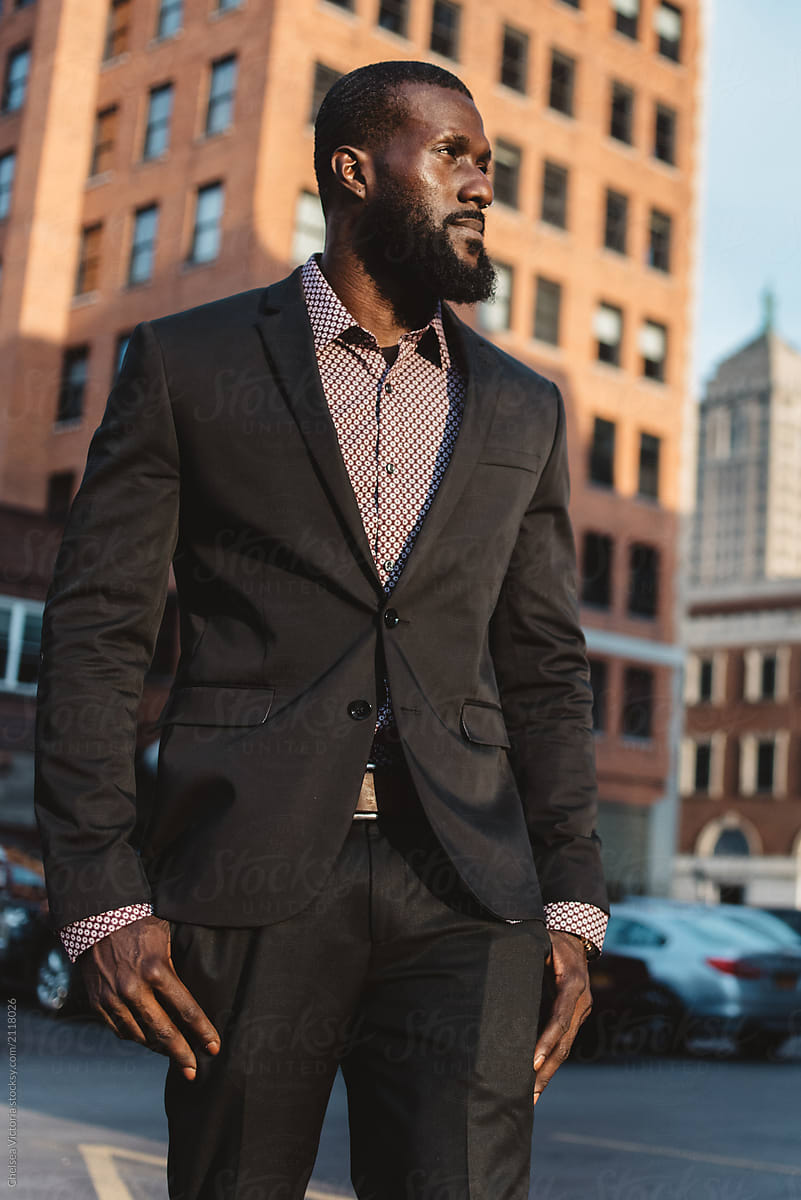 A young black man in the city wearing a suit