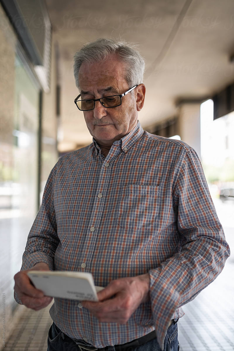 senior man looking at his bank account balance on the street