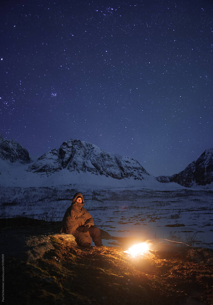 Female hiker sitting around campfire on a cold  winter evening