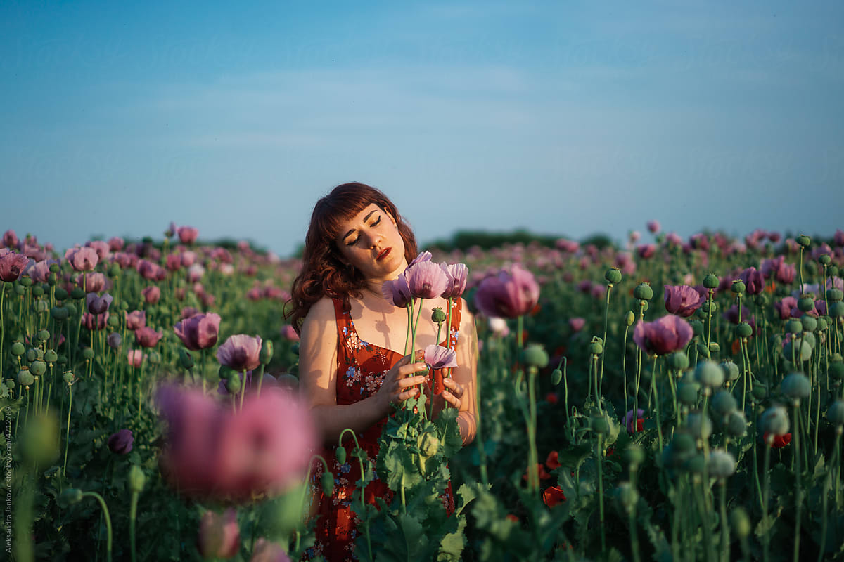 Portrait Of A Redhead Woman In The Flower Field Against The Blue Sky
