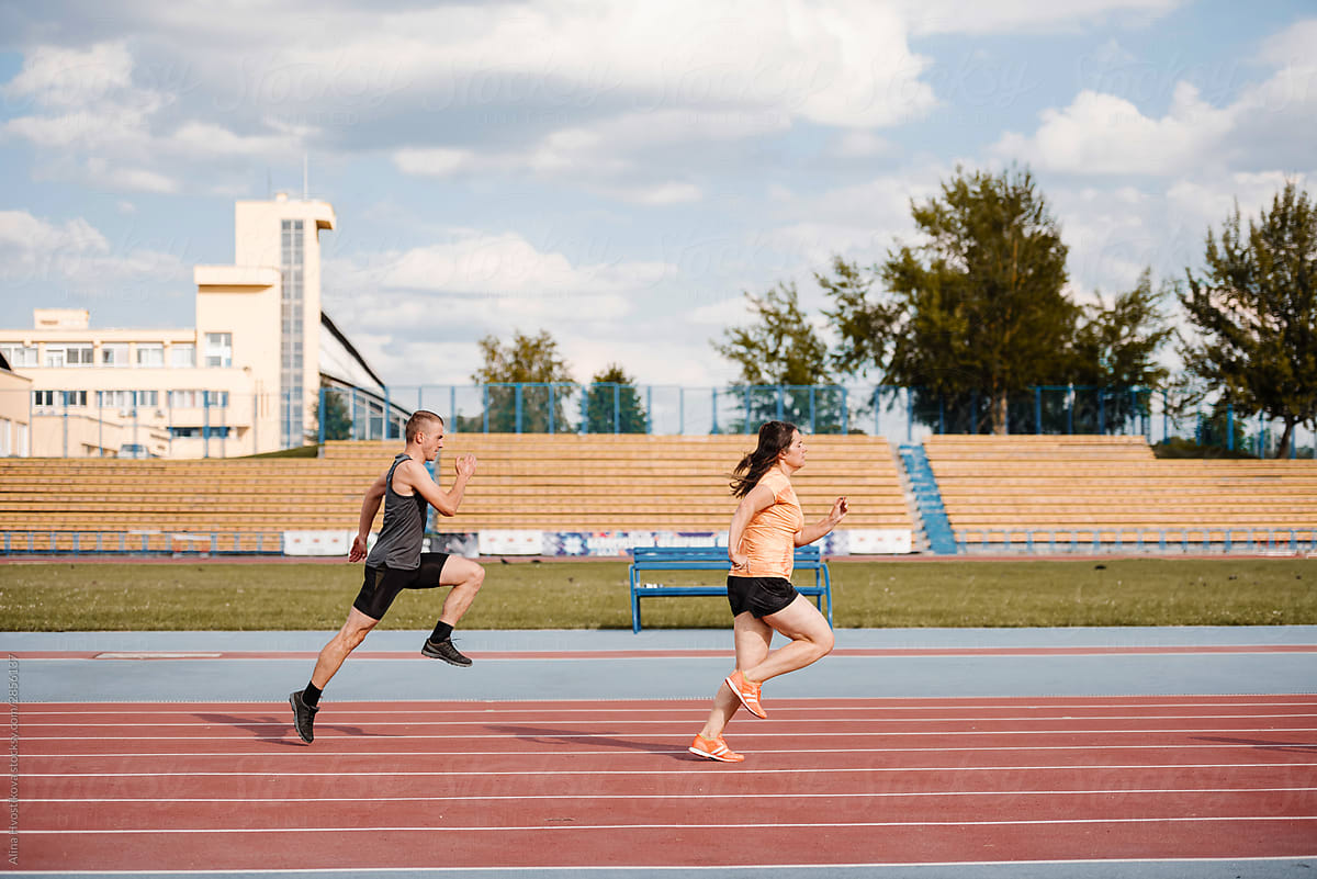 Sportive man and woman running at stadium