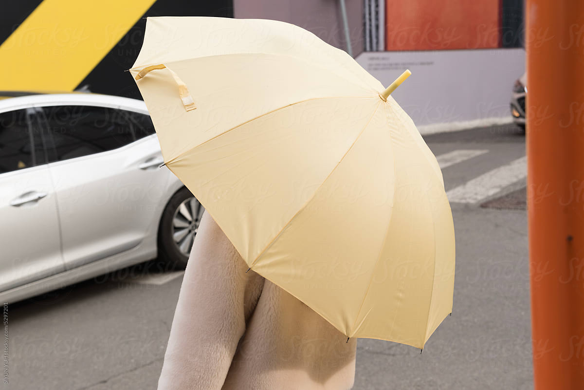 A woman with umbrella waiting on the street