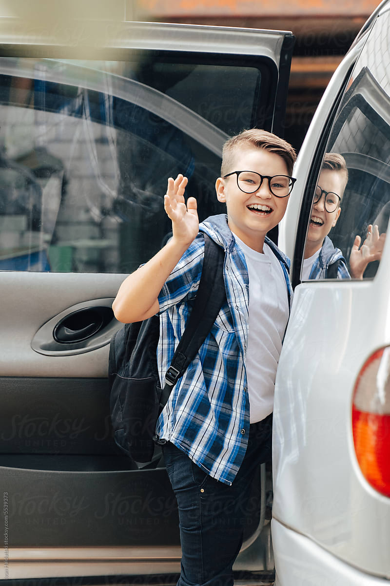 Portrait of smiling teen pupil boy getting ready for school by car