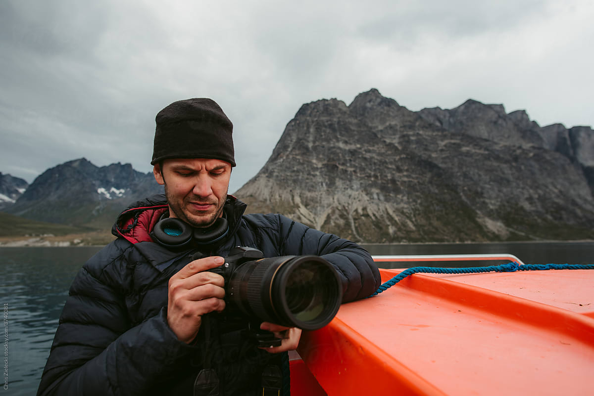 Male photographer checking camera near boat