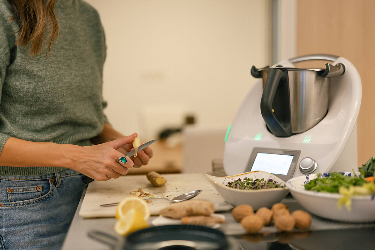 Woman using kitchen robot to prepare juice