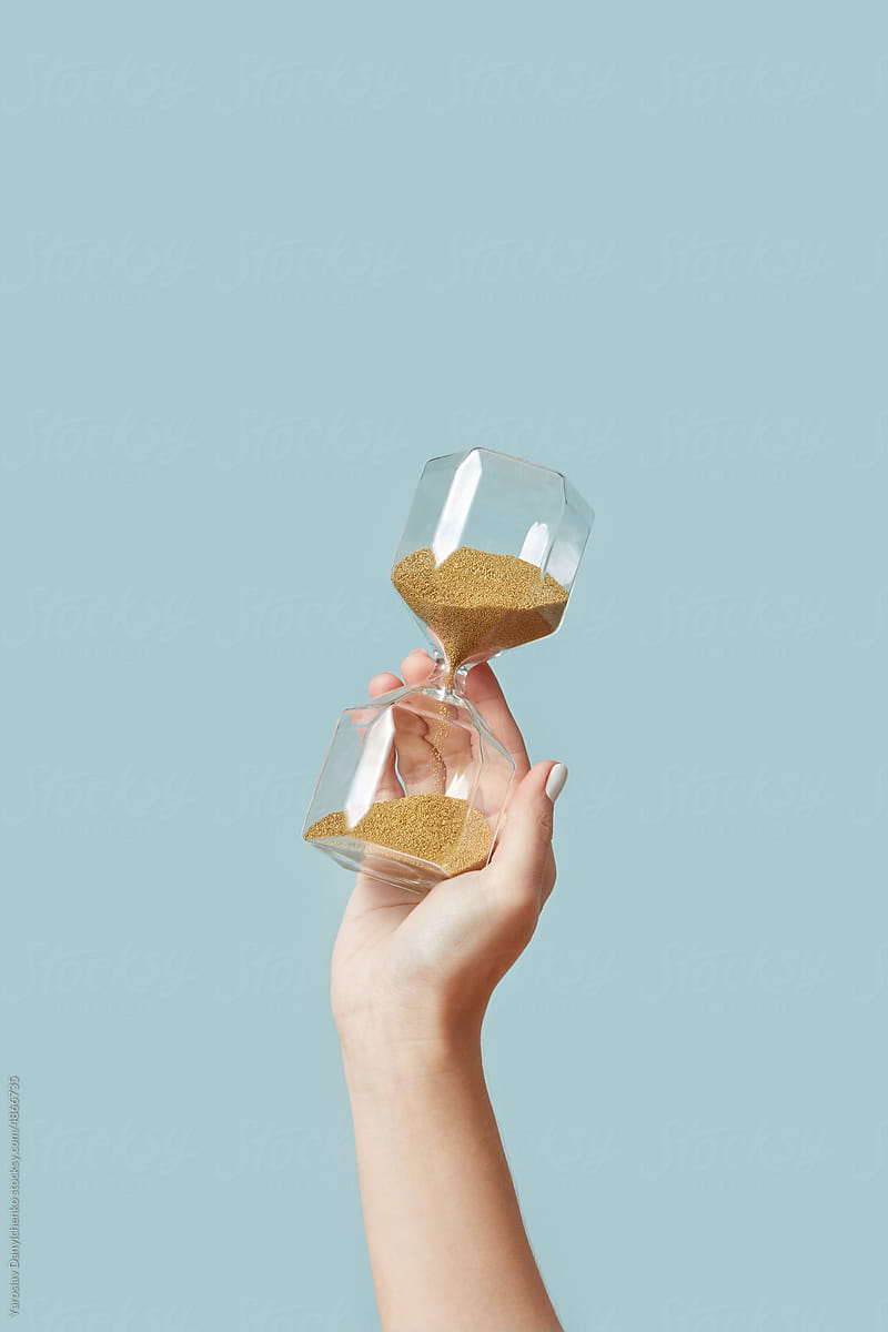 Sandglass with golden sand in woman\'s hand.