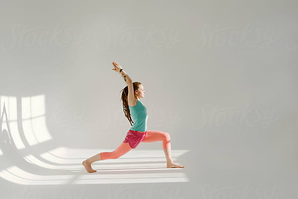 Slim Woman Lunging During Yoga Lesson by Stocksy Contributor