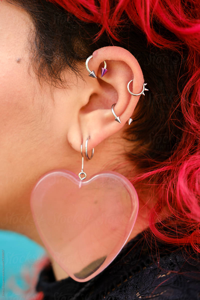 Detail shot of pierced ear with earrings and red hair