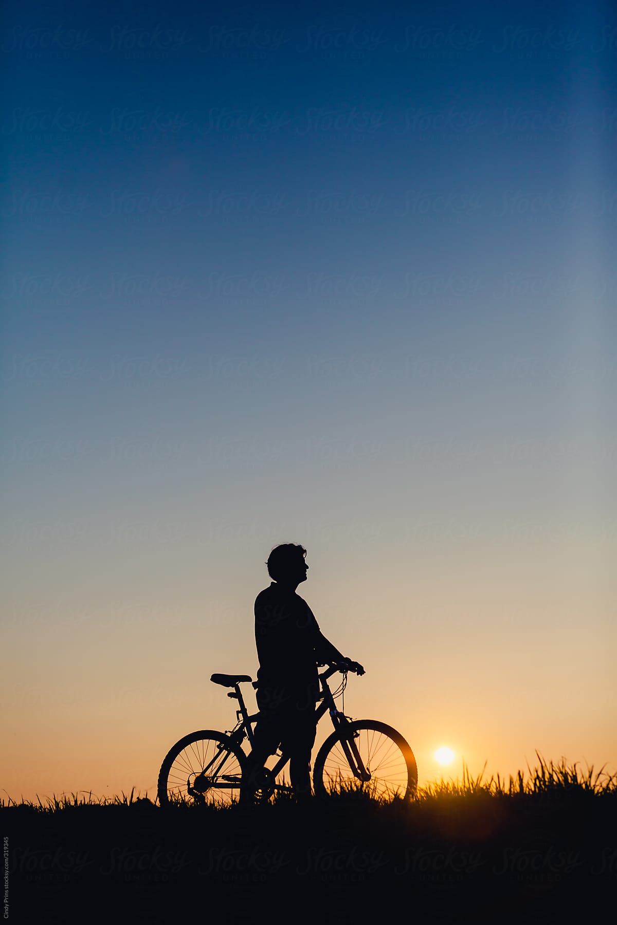 Silhouette of a man on a bike in a field during sunset