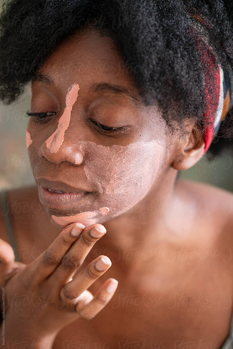 Black woman applying clay mask during skincare routine