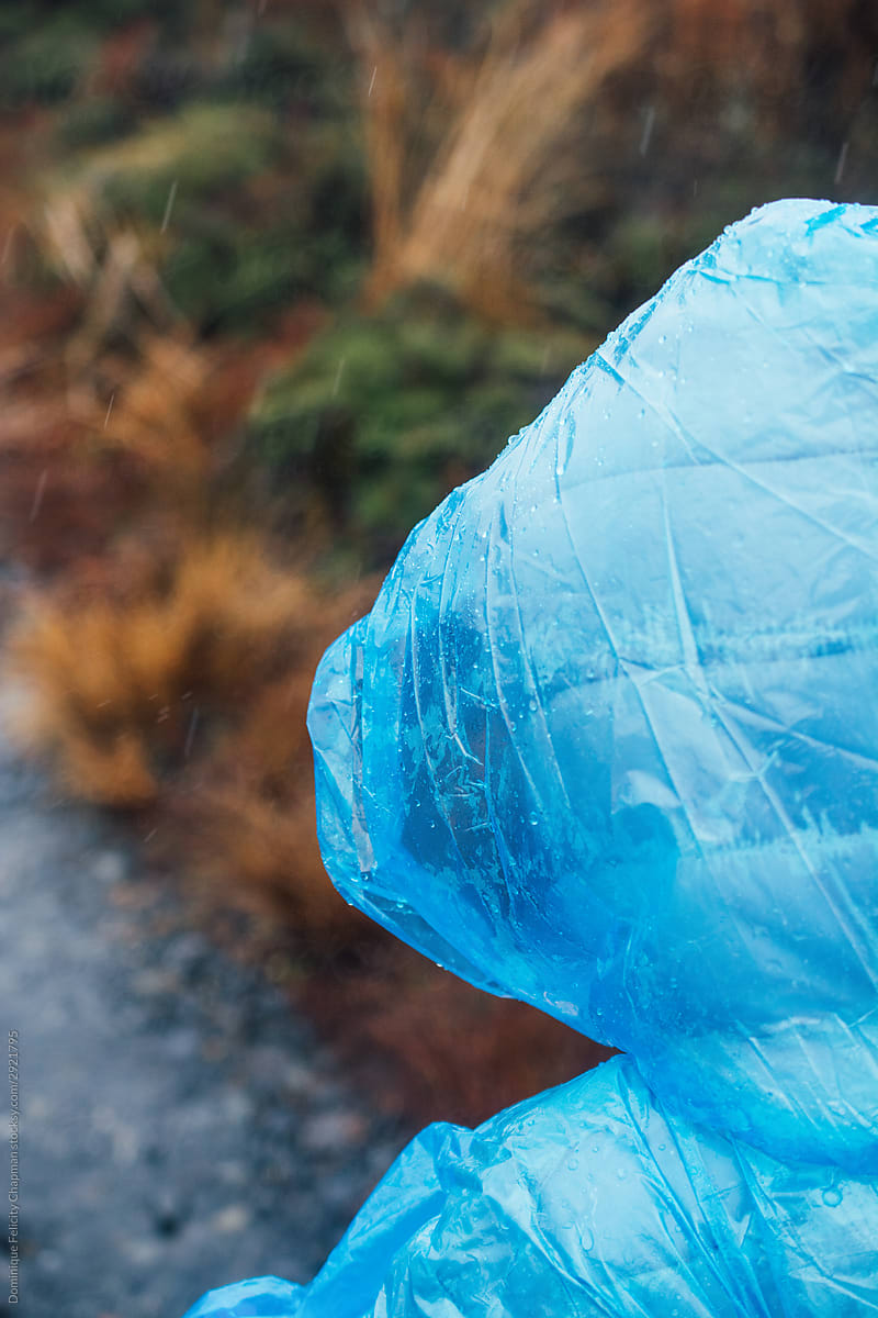 Close up of a girl wearing a blue plastic poncho while hiking