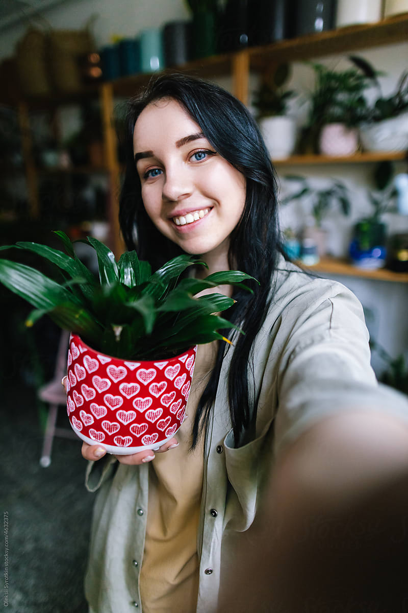 Client photographing herself with potted plant in floral shop