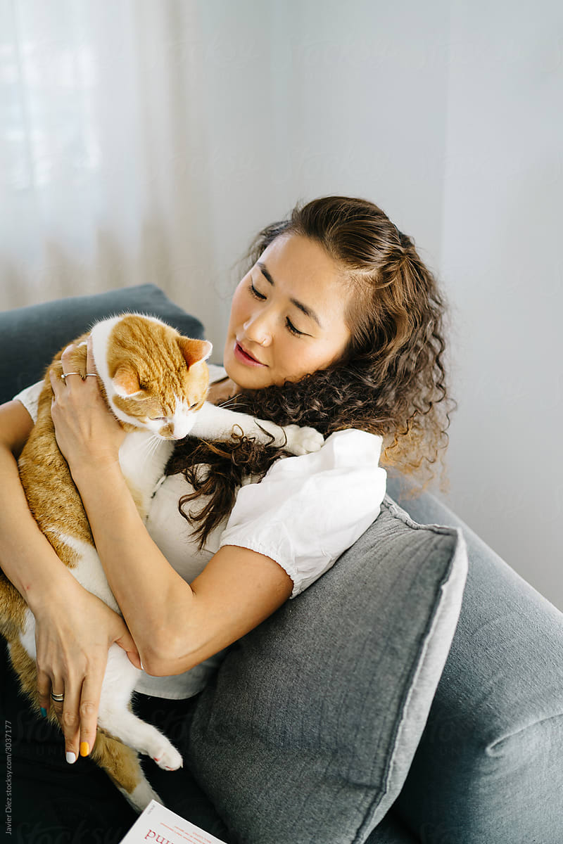 Asian female hugging cat on couch