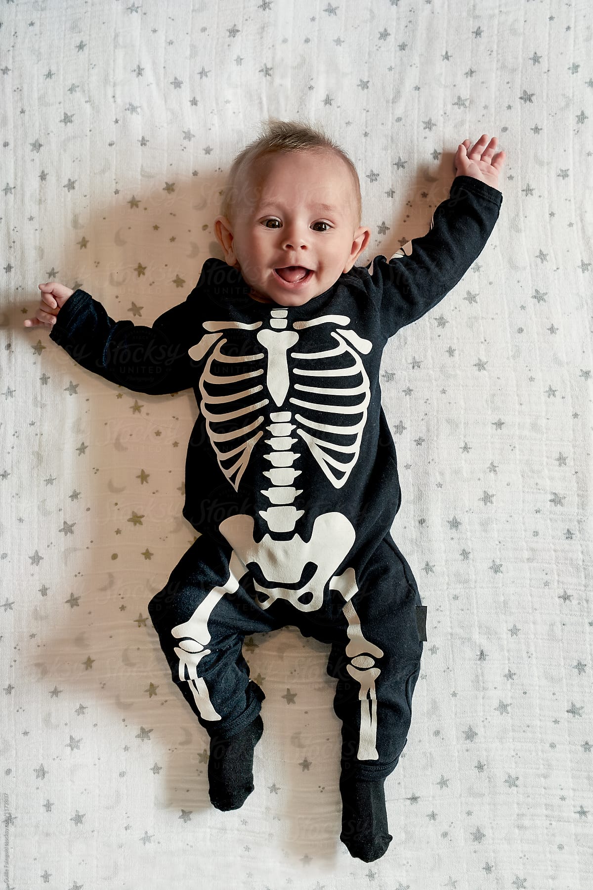 Cute baby in Halloween costume lying on bed