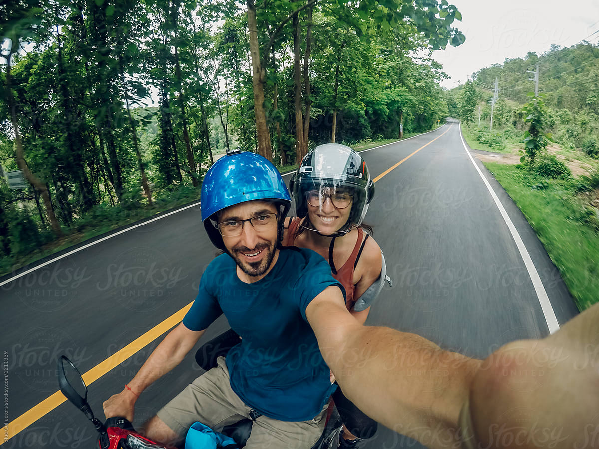 Happy couple on a motorbike traveling and taking a selfie