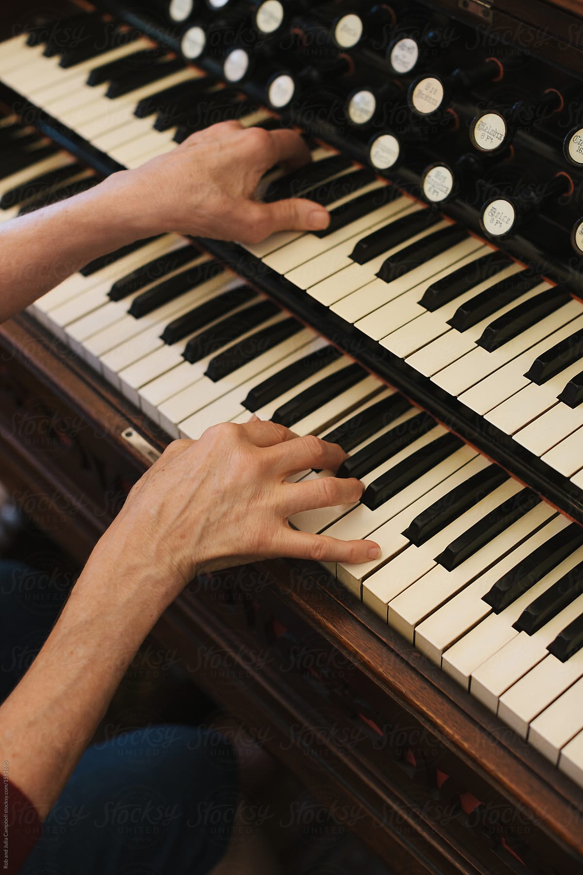Hands of mature woman playing piano and organ in home studio