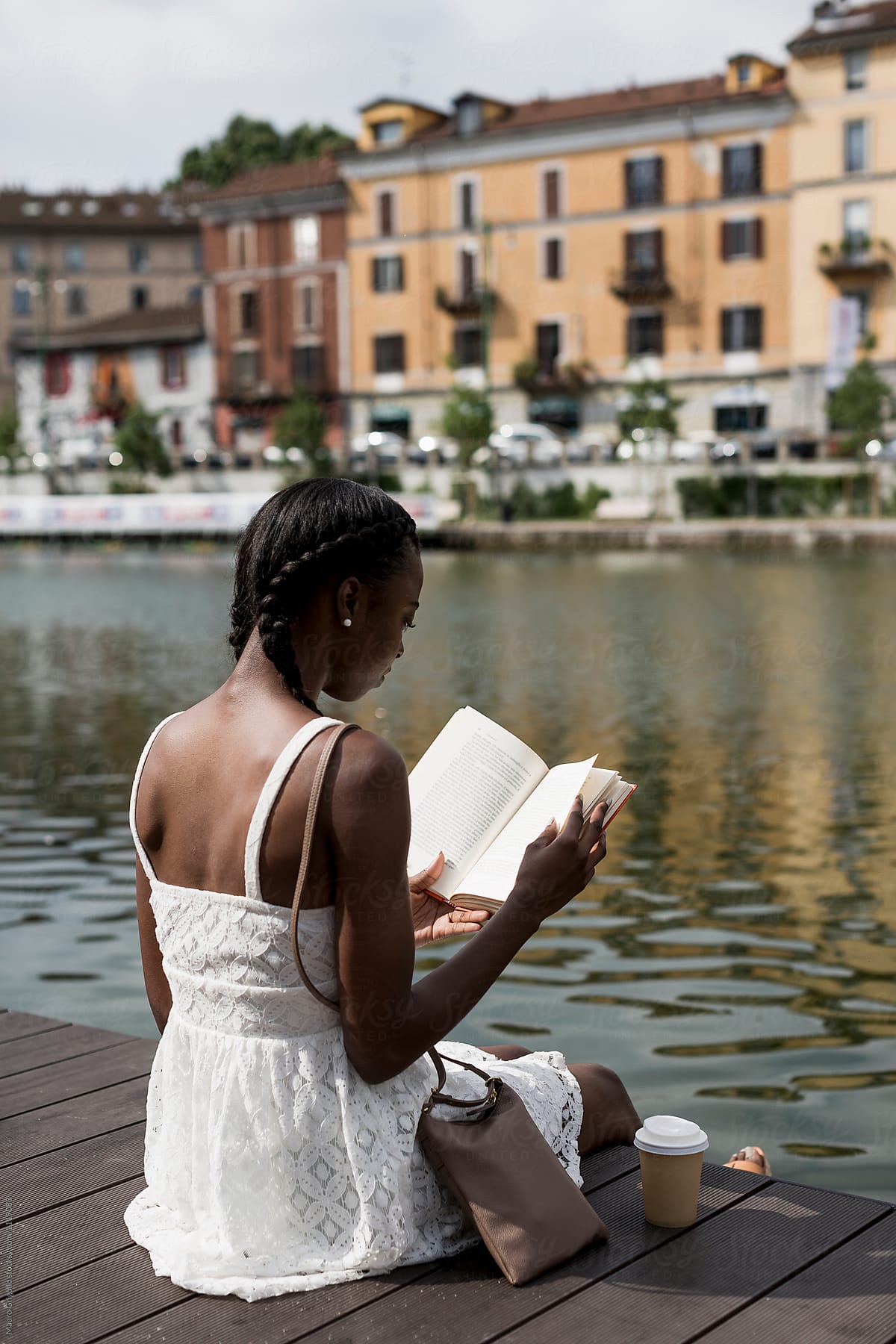 Black woman reading a book and sitting on a pier