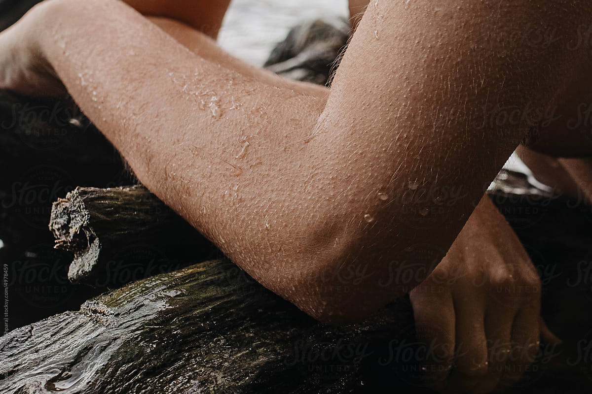 Close-up arms, hands and elbow of wet naked woman on wood in water