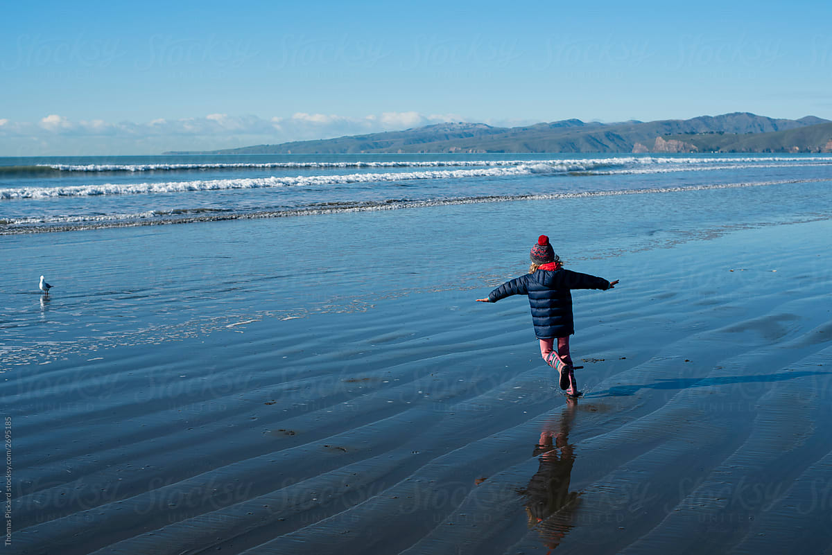 Young girl running at the beach. New Zealand.