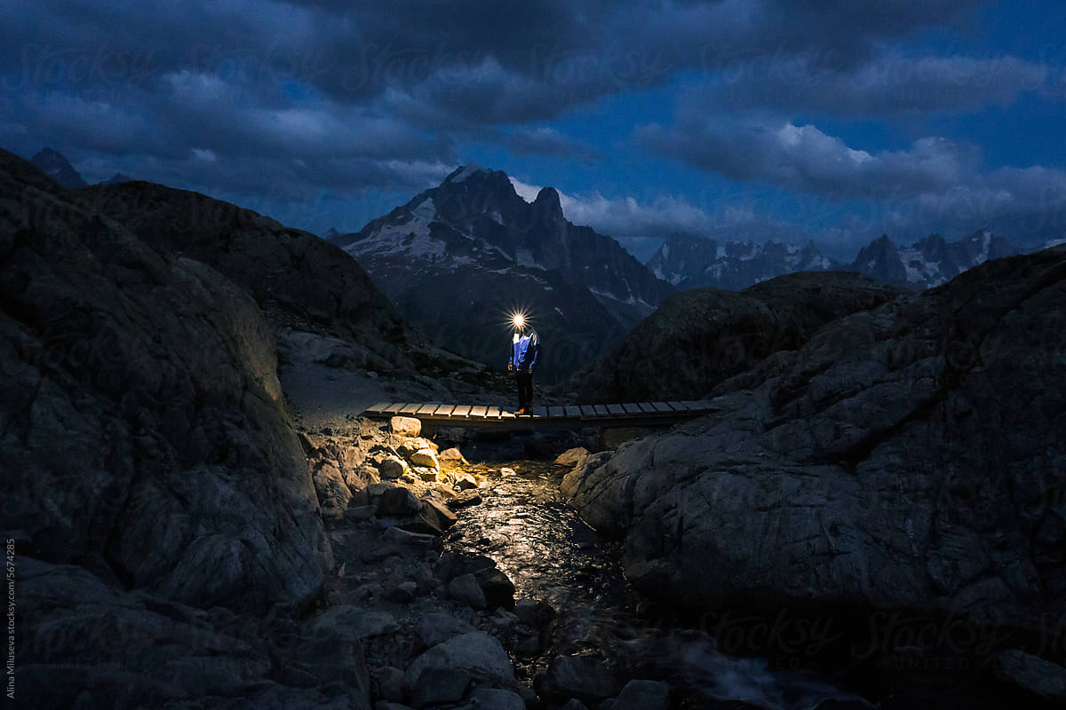 Man with headlamp against mountain ridge at twilight