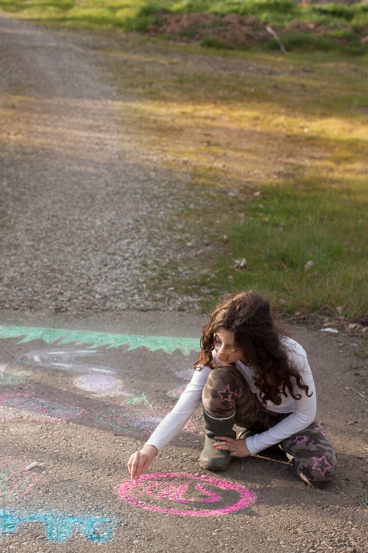 Girl drawing with chalk on a country road