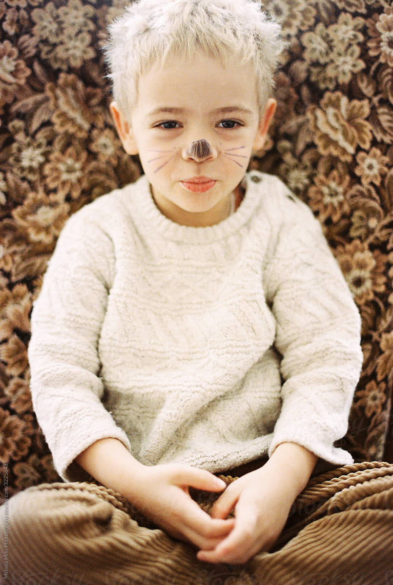 Toddler boy with face paint in a vintage chair