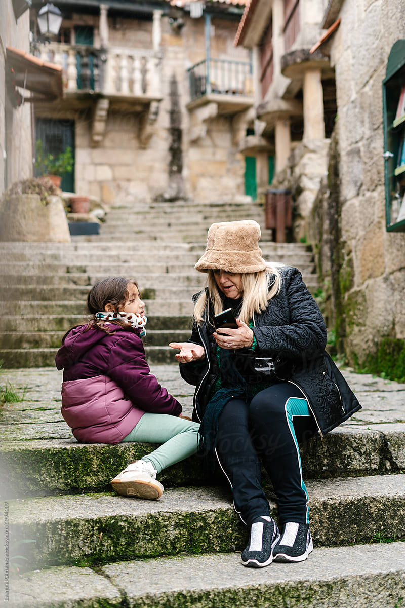 Grandmother and granddaughter using smartphone on steps