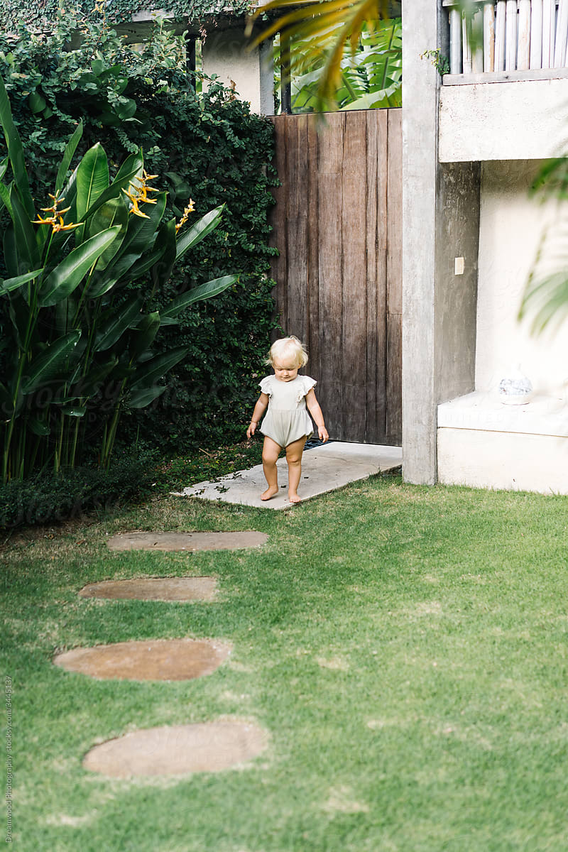 Little kid walking in yard of country house