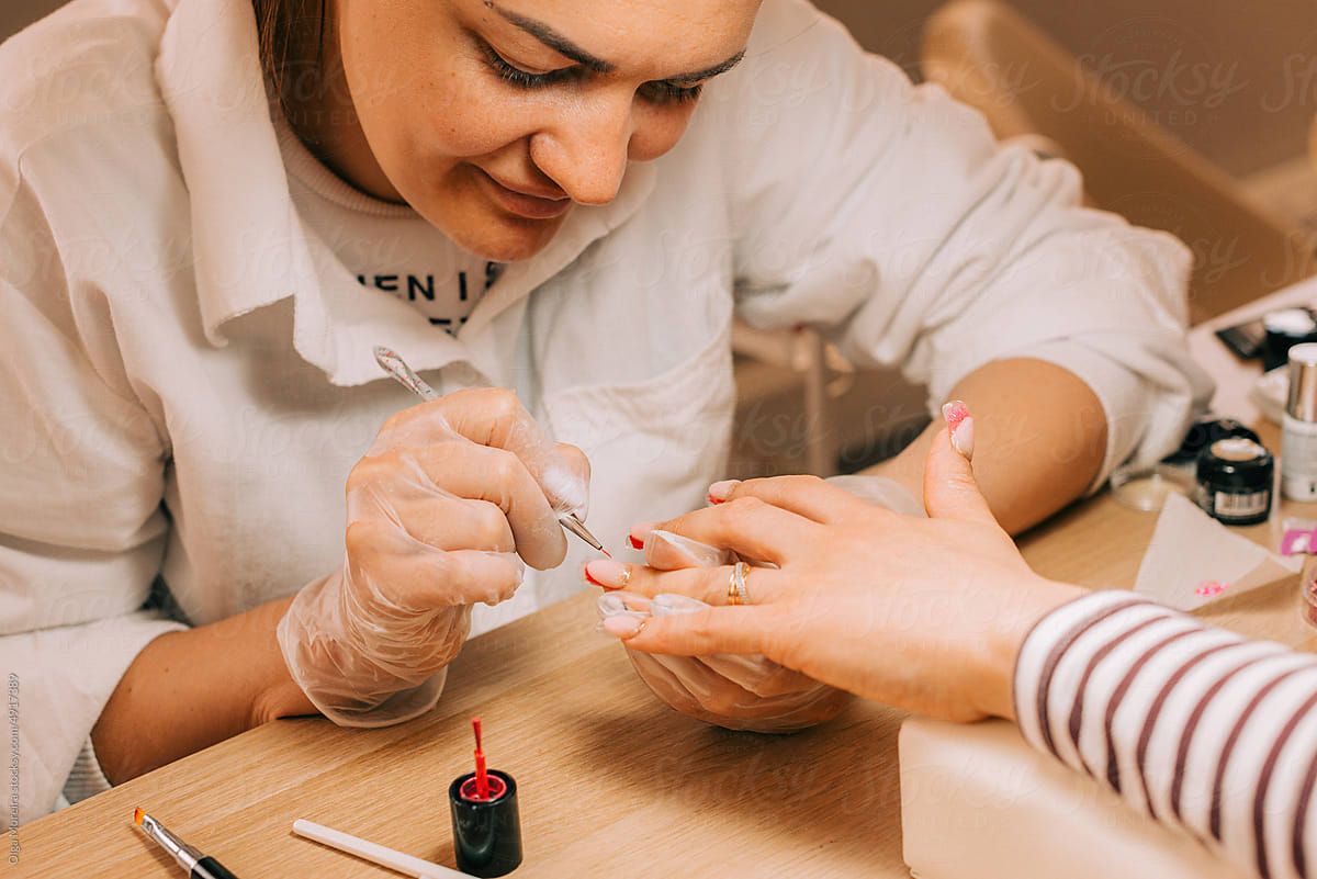 Female manicurist painting nails of a client