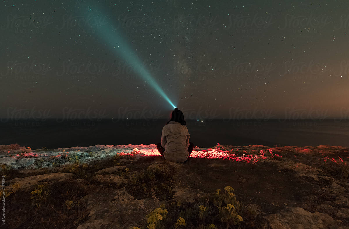 Anonymous woman looking at the stars with head torch