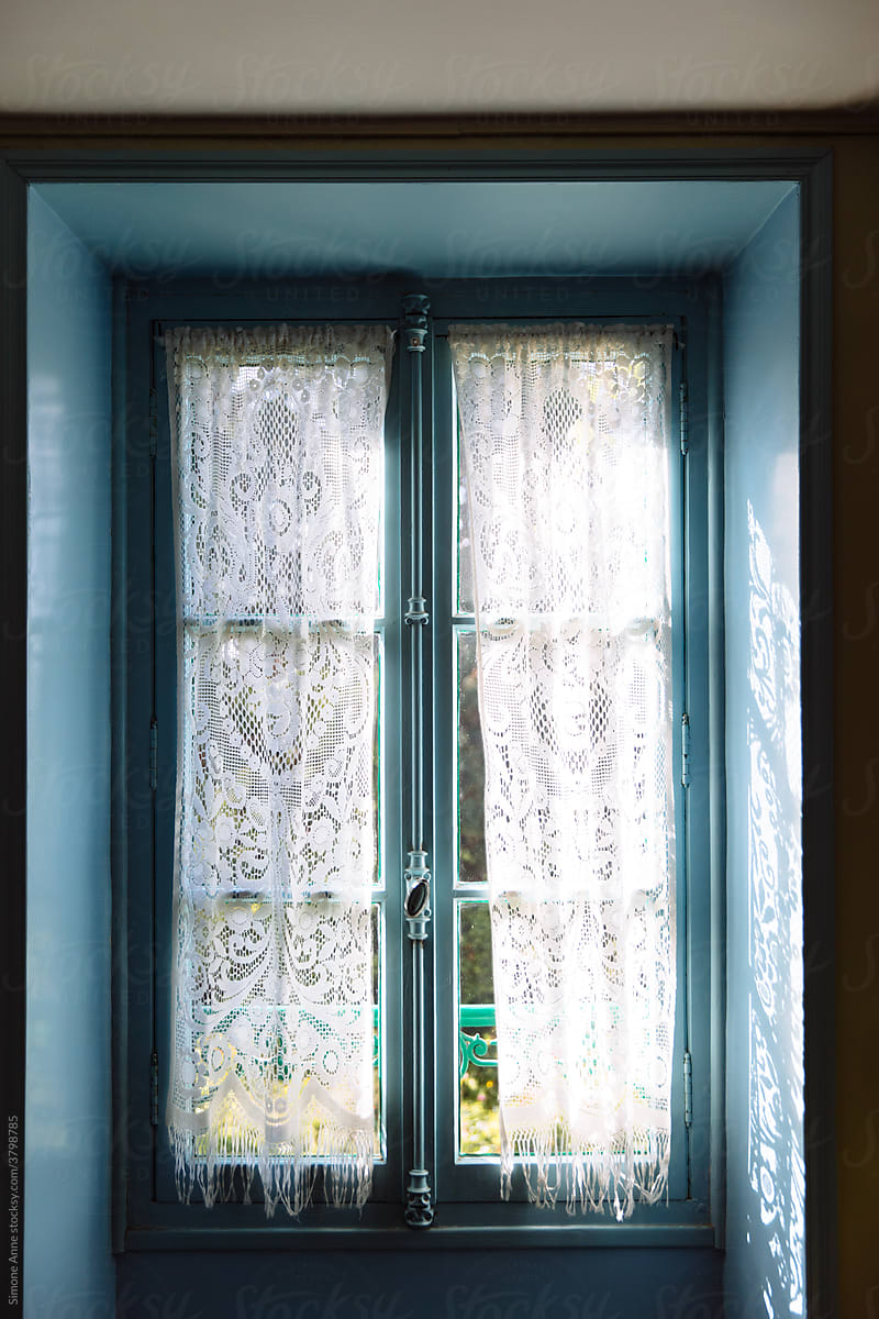 A blue window with a lace curtain