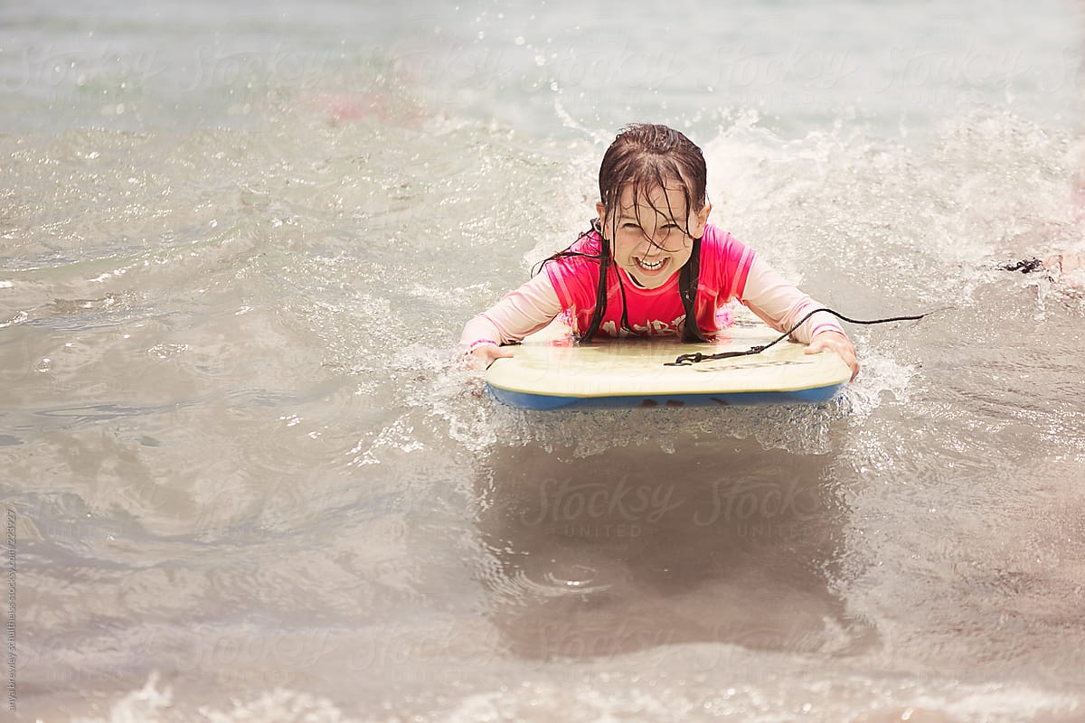 Laughing child on a body board surfing happily