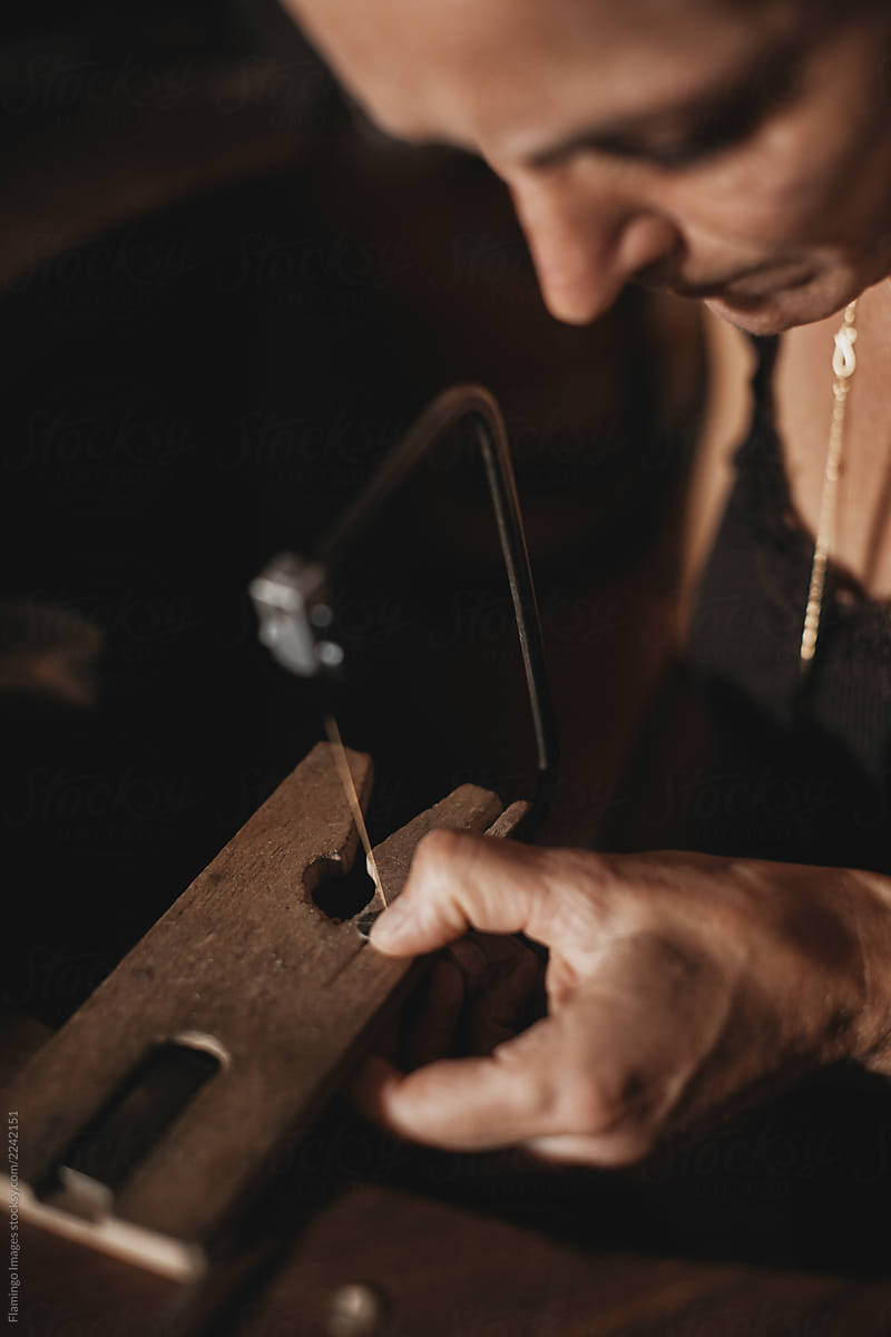 Female jeweler using a saw in her studio