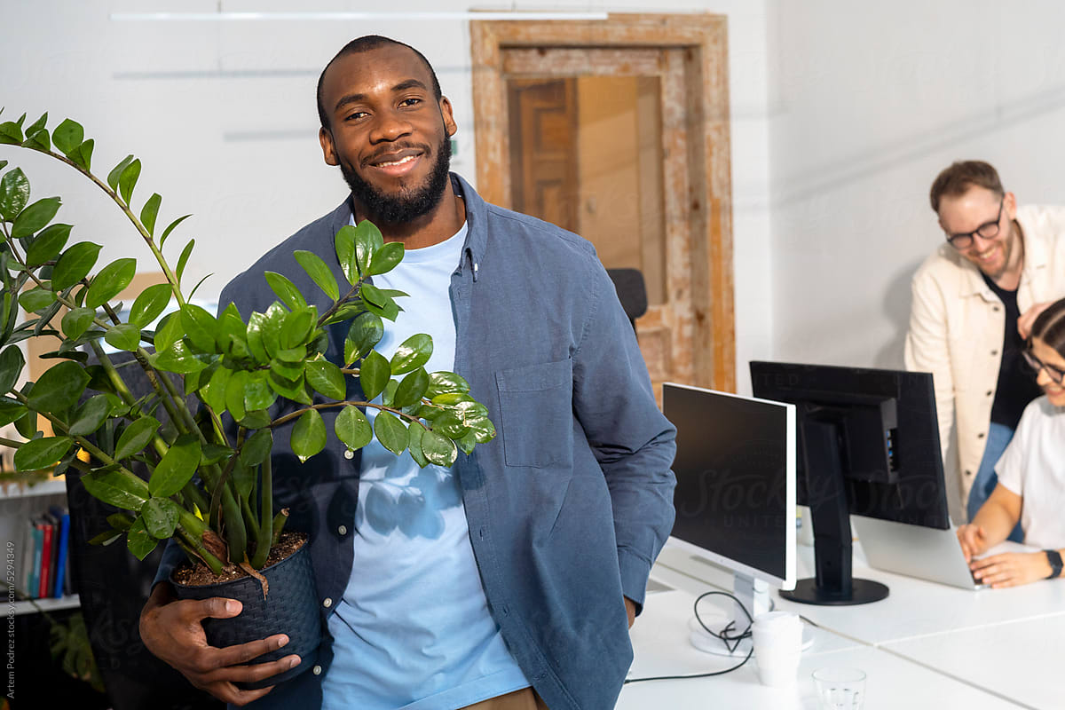 Film photo of a portrait of a man in the office holding a house plant