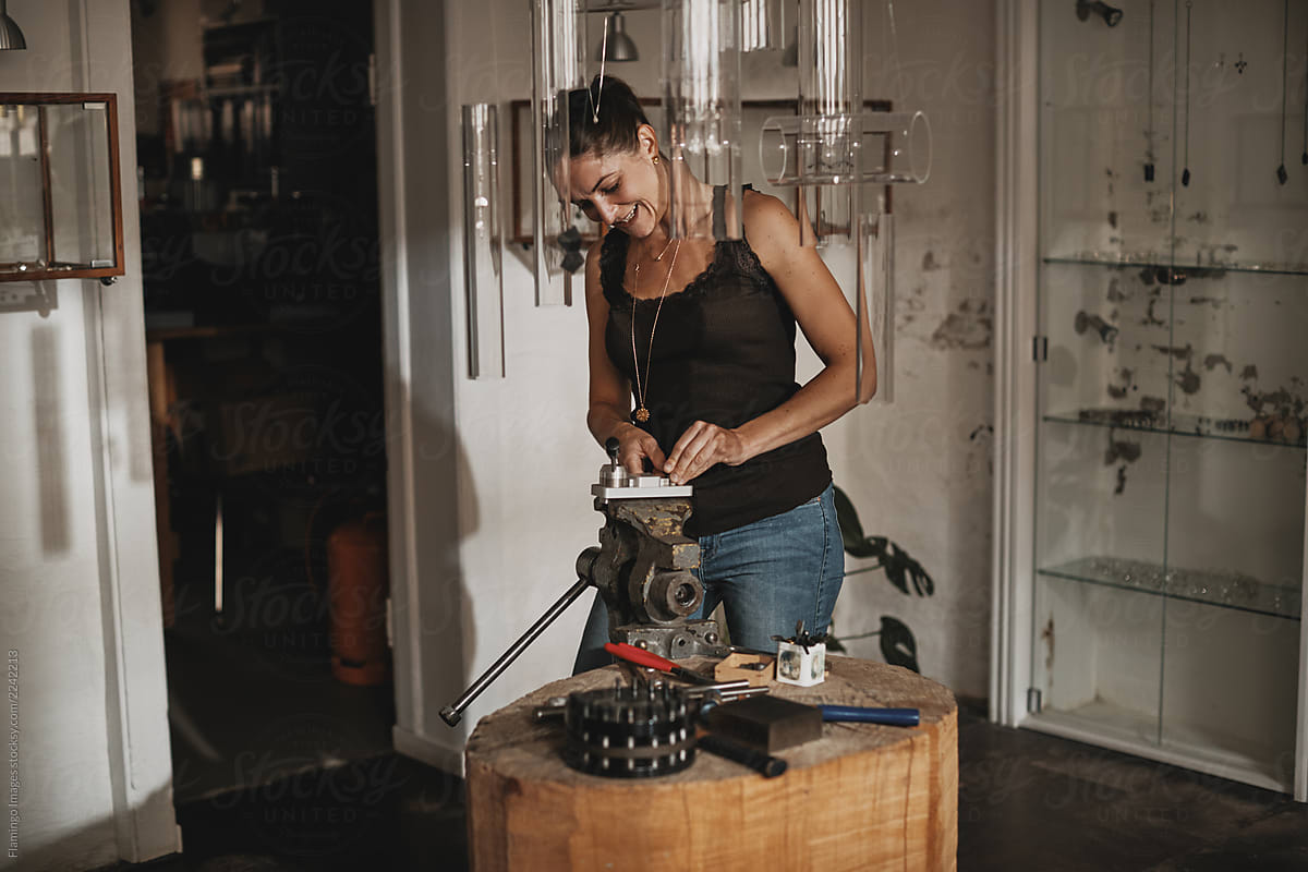 Smiling female artisan making jewelry in her studio
