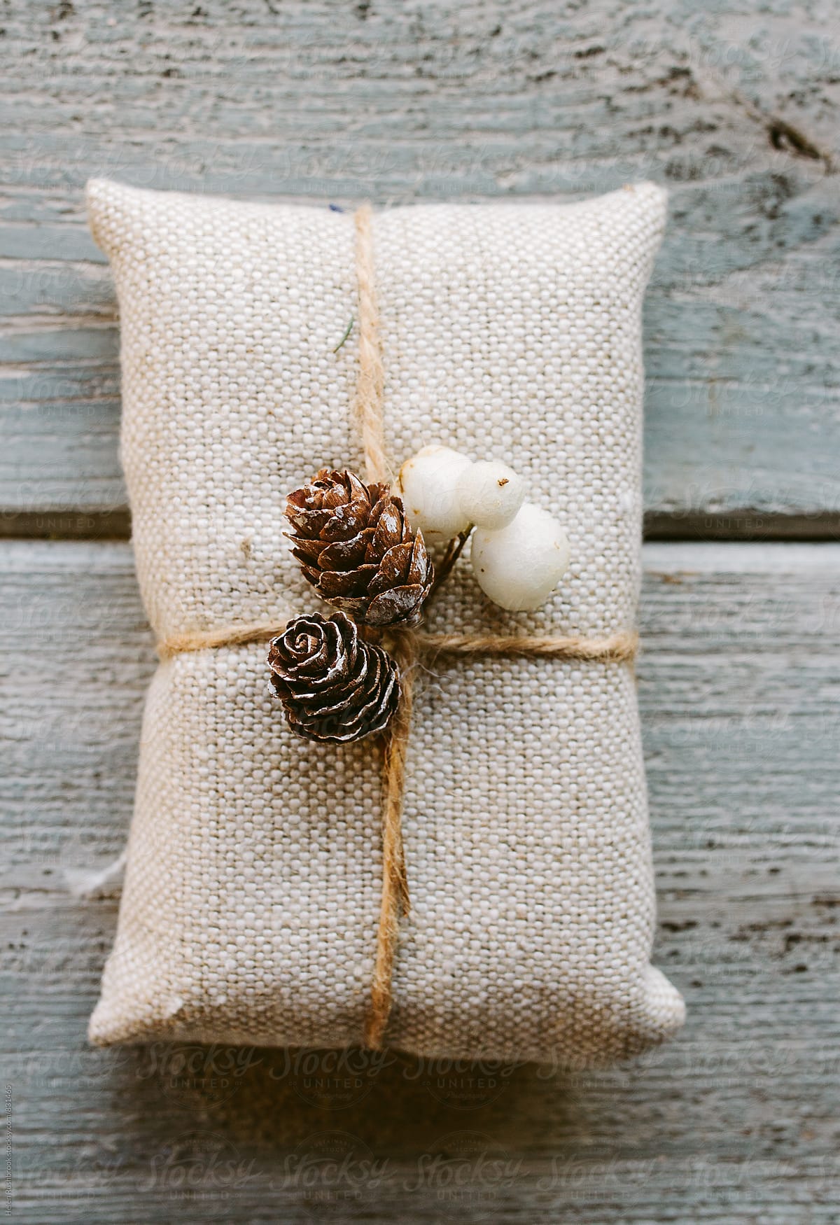 Christmas gift wrapped with linen and decorated with natural items.