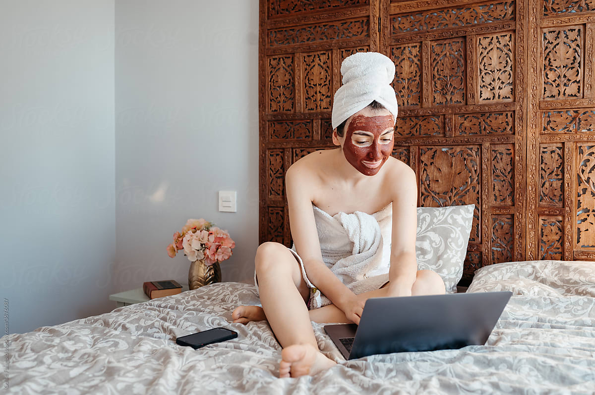 Woman with face mask using laptop.