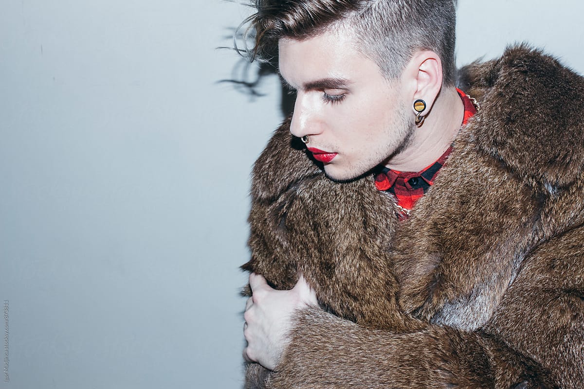 beautiful young man with red lipstick and golden necklace in a Fur Coat , fashion , hairstyle