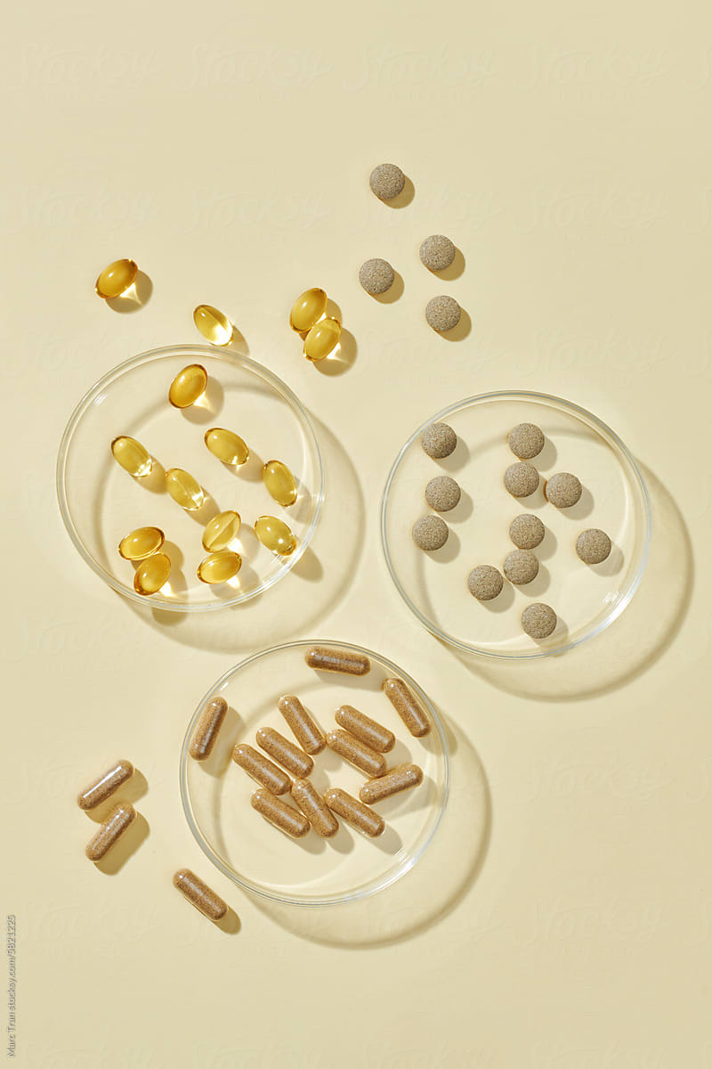 Pills showcased on petri dishes on light yellow background