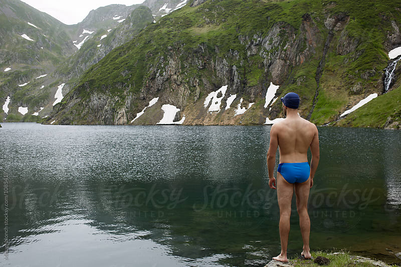 Young man swimmer getting ready for training in a lake