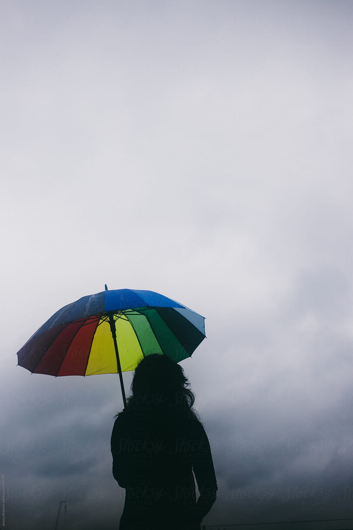 Young Woman With A Rainbow Color Umbrella In The Rain By