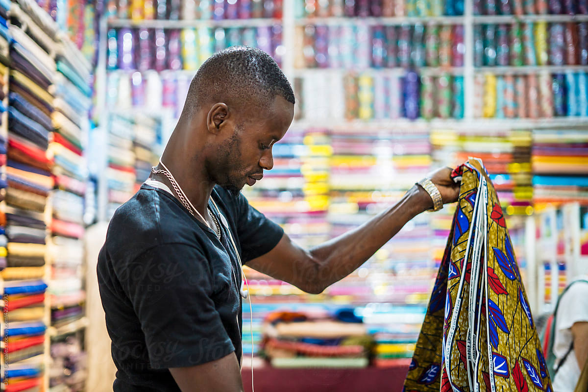 Black man stacking fabric in shop