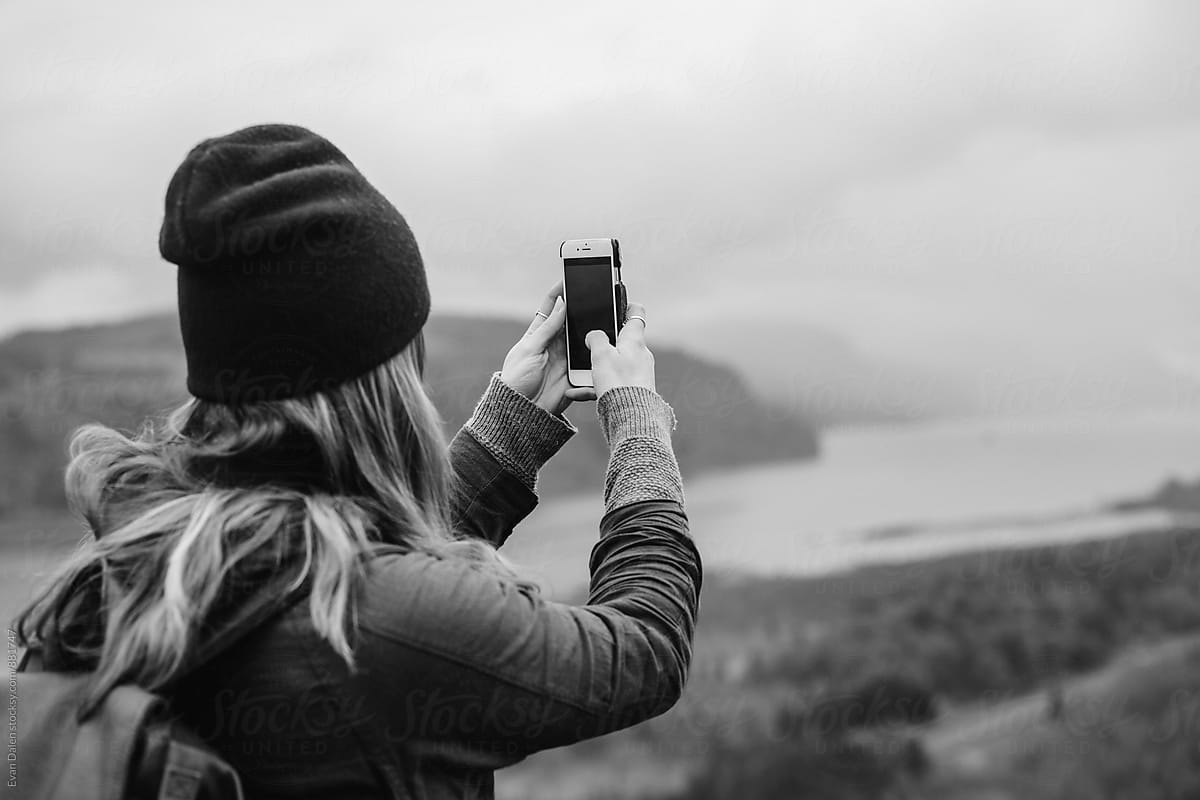 Young Woman Taking Photo With Phone On Cliff