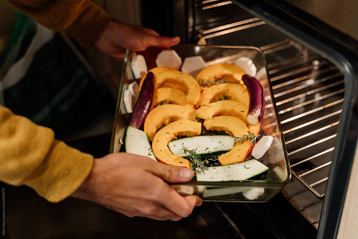 Man placing  veggies tray inside the oven