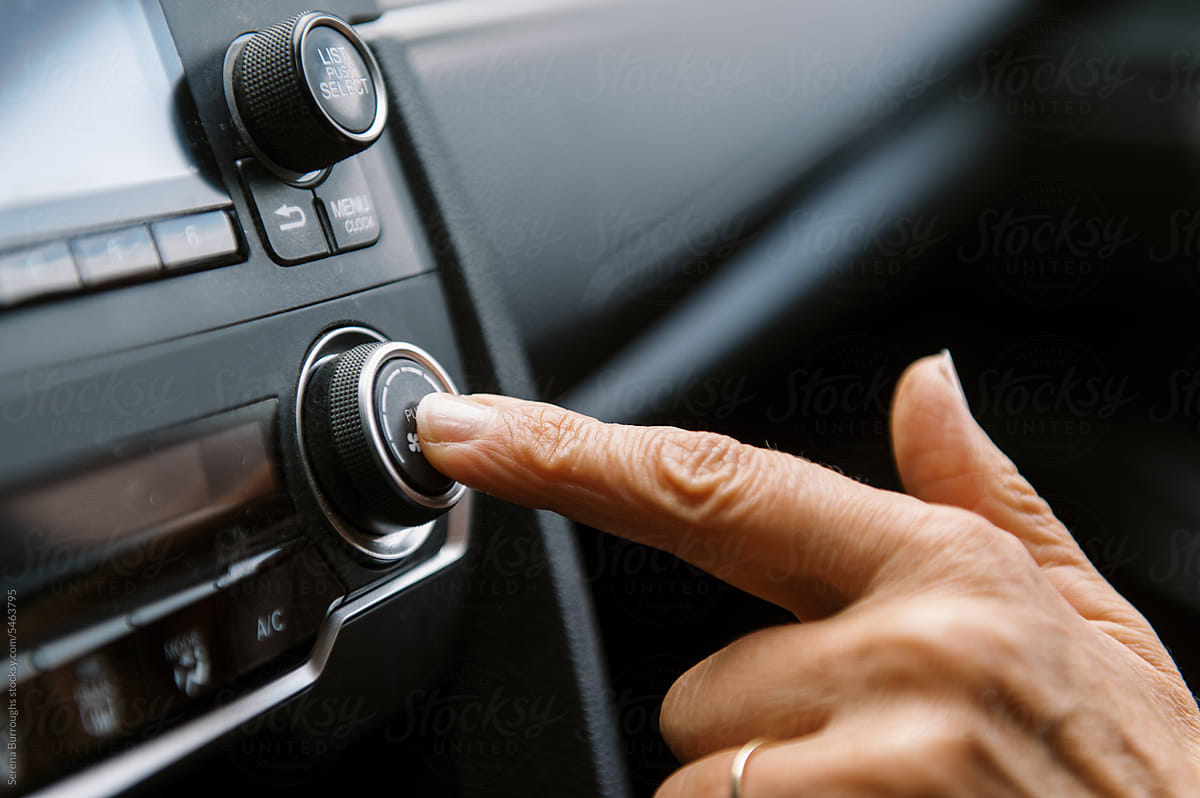 middle aged woman inside a car pushing button